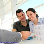 Couple in real-estate agency signing property loan contract